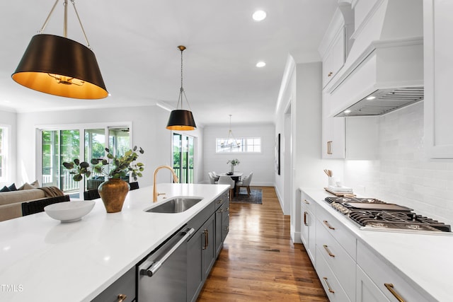 kitchen with recessed lighting, wood finished floors, a sink, appliances with stainless steel finishes, and custom exhaust hood