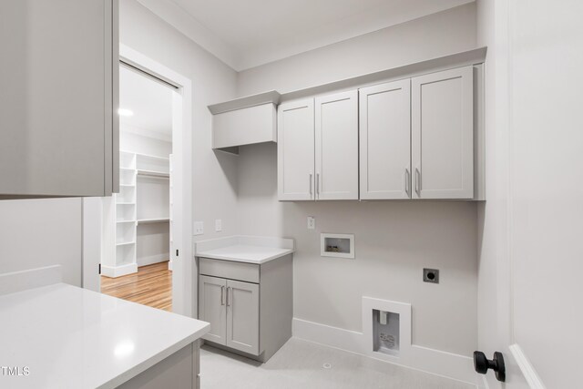 clothes washing area featuring electric dryer hookup, cabinet space, hookup for a washing machine, and baseboards