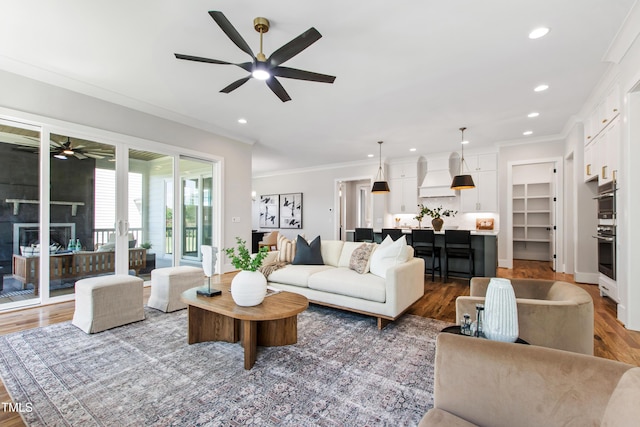 living room with wood finished floors, recessed lighting, ceiling fan, and crown molding