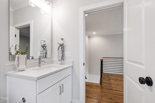 bathroom with baseboards, wood finished floors, vanity, and ornamental molding