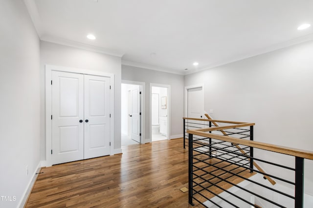 interior space featuring baseboards, recessed lighting, an upstairs landing, wood finished floors, and crown molding