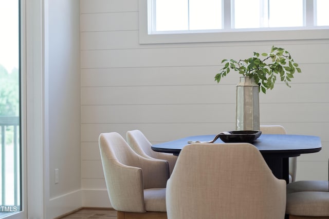 dining area featuring wood finished floors and wooden walls