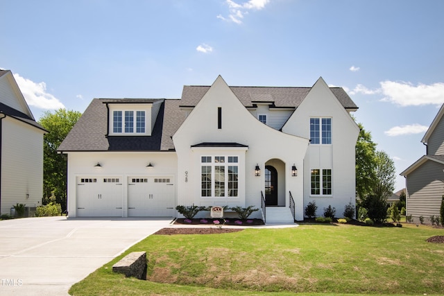 view of front of home with a garage, driveway, a front yard, and roof with shingles