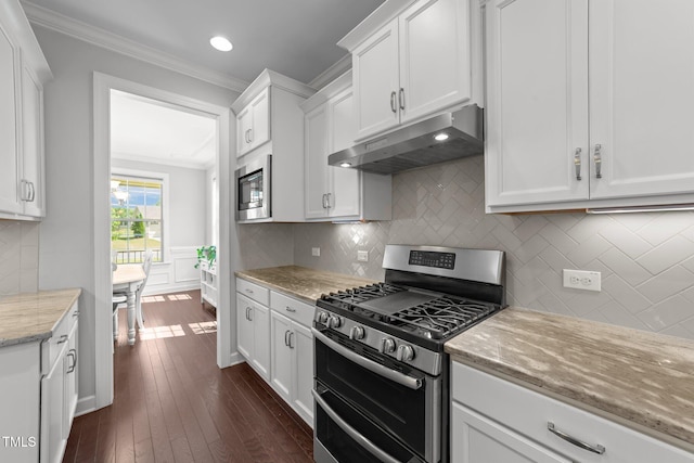 kitchen with appliances with stainless steel finishes, under cabinet range hood, crown molding, white cabinets, and light stone countertops