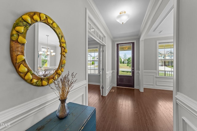 foyer with plenty of natural light, a chandelier, ornamental molding, hardwood / wood-style flooring, and wainscoting