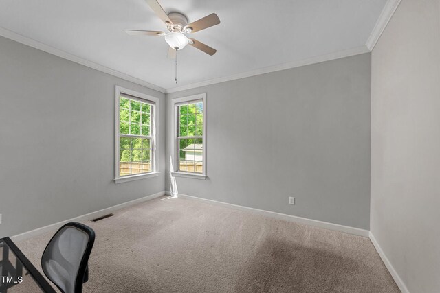 carpeted empty room with ornamental molding, ceiling fan, baseboards, and a desk