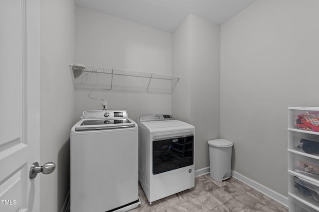 laundry room with independent washer and dryer, baseboards, and light marble finish flooring