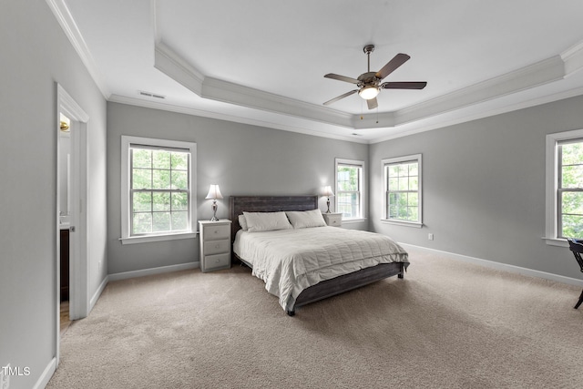 bedroom with ornamental molding, a tray ceiling, baseboards, carpet floors, and ceiling fan