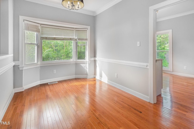 unfurnished room with wood-type flooring, ornamental molding, and visible vents