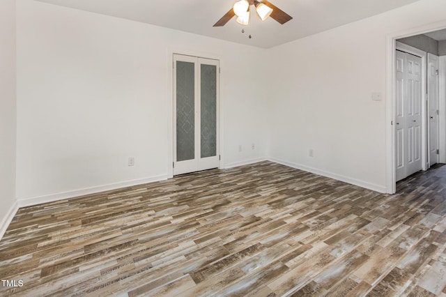 unfurnished room featuring wood finished floors, baseboards, and a ceiling fan