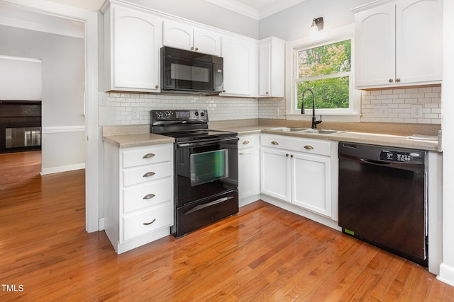 kitchen featuring crown molding, a sink, white cabinetry, and black appliances