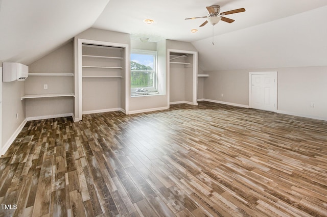 additional living space featuring ceiling fan, a wall unit AC, vaulted ceiling, wood finished floors, and baseboards
