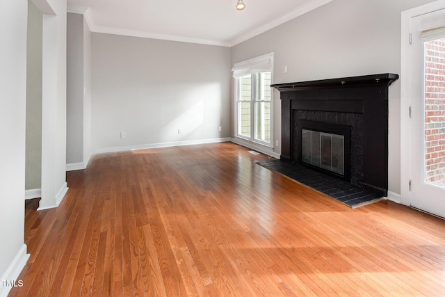 unfurnished living room with crown molding, baseboards, hardwood / wood-style floors, and a glass covered fireplace