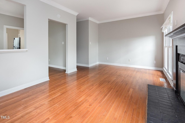 unfurnished living room featuring ornamental molding, baseboards, light wood-style floors, and a brick fireplace
