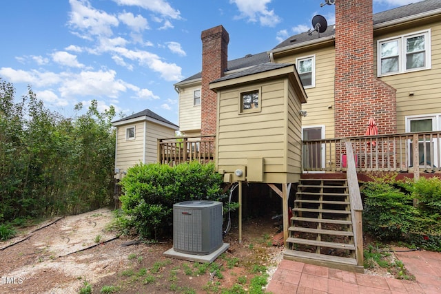 back of house with stairs, a deck, cooling unit, and a chimney