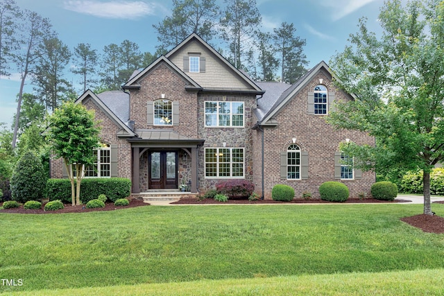 craftsman house with french doors, a front yard, and brick siding