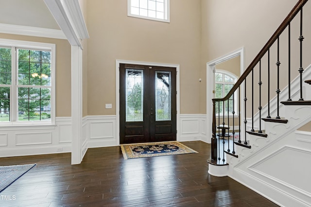 foyer entrance featuring healthy amount of natural light, wainscoting, stairway, a decorative wall, and dark wood-type flooring