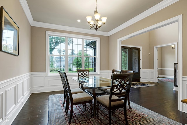 dining space with a chandelier, wainscoting, dark wood-style floors, crown molding, and a decorative wall