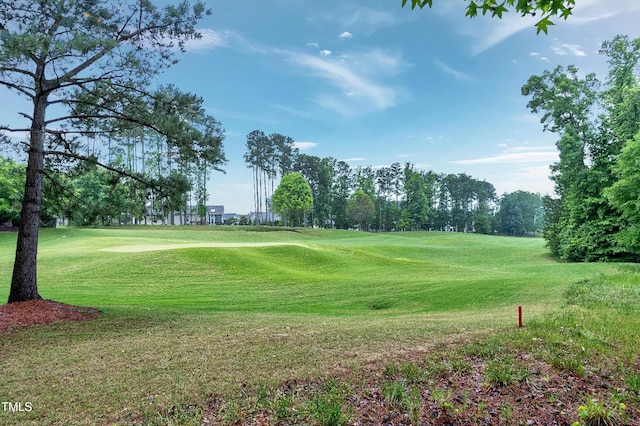 view of property's community with view of golf course and a lawn
