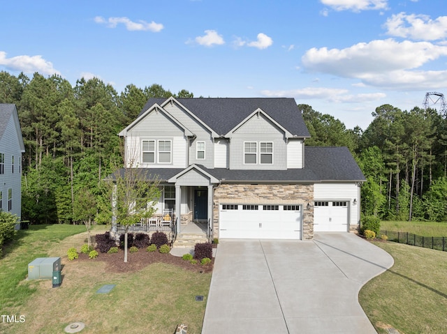 view of front facade with covered porch, concrete driveway, a front yard, and stone siding