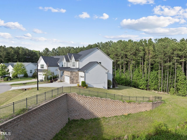 exterior space with an attached garage, fence, stone siding, concrete driveway, and a lawn