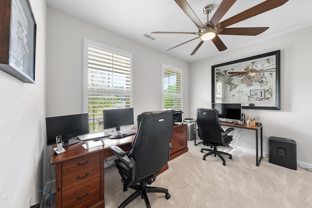 office space featuring baseboards, a ceiling fan, light colored carpet, and visible vents