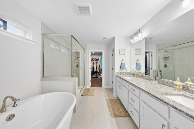 bathroom with a sink, a walk in closet, double vanity, and visible vents