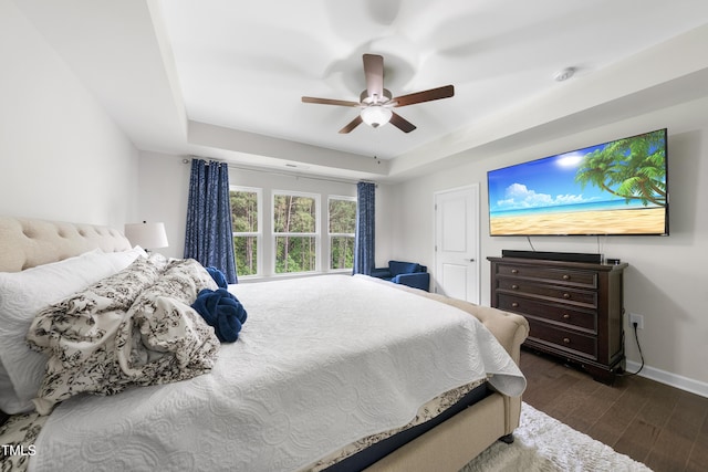 bedroom with a ceiling fan, baseboards, dark wood finished floors, and a raised ceiling