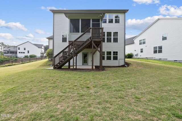 rear view of house featuring a sunroom, a lawn, fence, and stairway