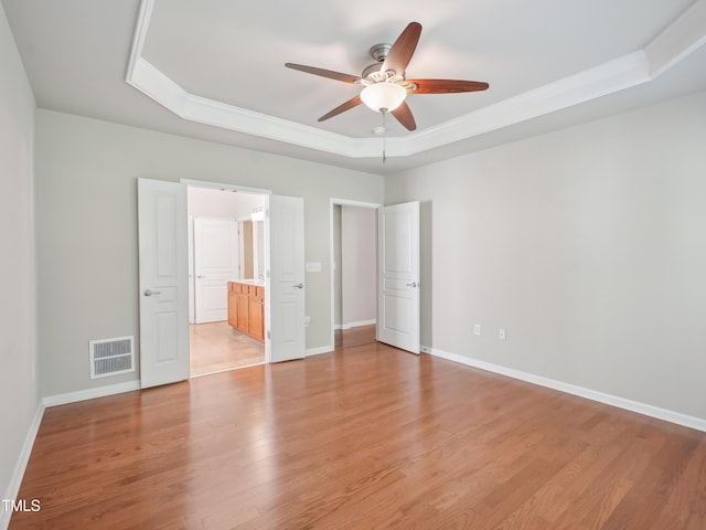 519 Garendon Dr, Cary, NC 27519 - unfurnished bedroom with visible vents, baseboards, ornamental molding, a tray ceiling, and light wood-style flooring