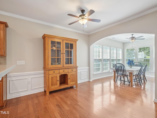 519 Garendon Dr, Cary, NC 27519 - dining area featuring ceiling fan, arched walkways, a wainscoted wall, light wood-style floors, and ornamental molding