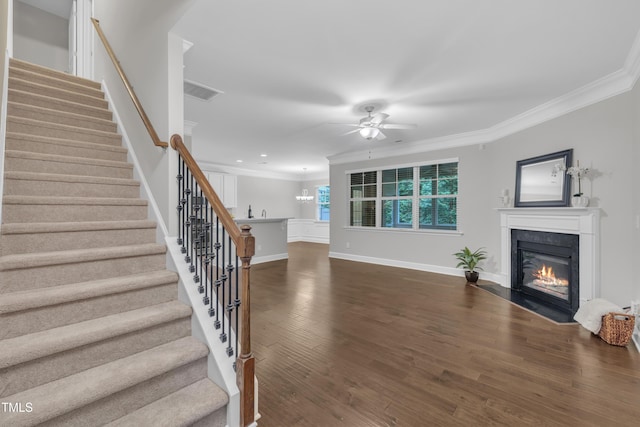 unfurnished living room with ceiling fan, crown molding, a fireplace with flush hearth, stairs, and baseboards