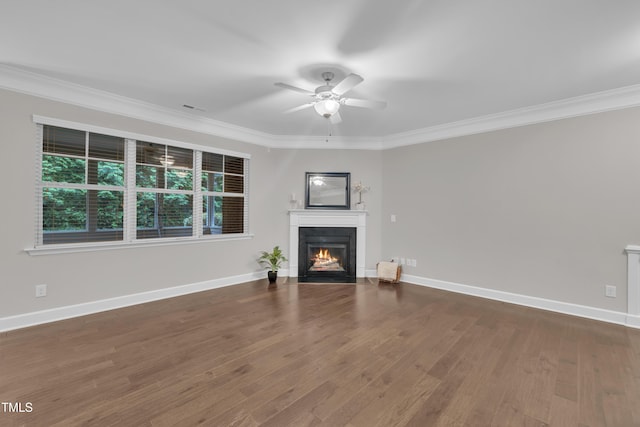 unfurnished living room with crown molding, a ceiling fan, a fireplace with flush hearth, wood finished floors, and baseboards
