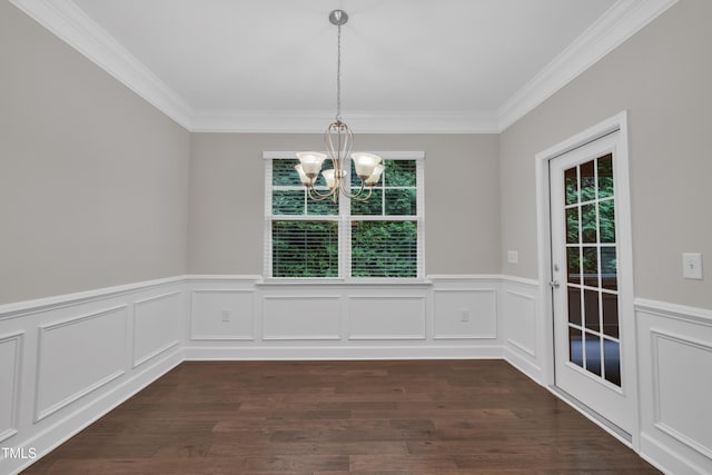 unfurnished dining area with a chandelier, ornamental molding, wainscoting, dark wood-type flooring, and a decorative wall