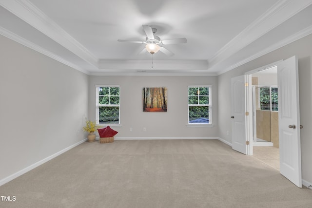unfurnished room with a tray ceiling, light carpet, plenty of natural light, ceiling fan, and ornamental molding