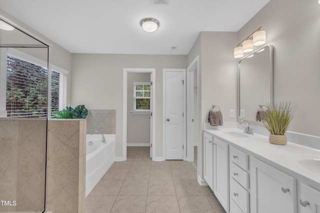 full bathroom with a bath, double vanity, tile patterned floors, and baseboards