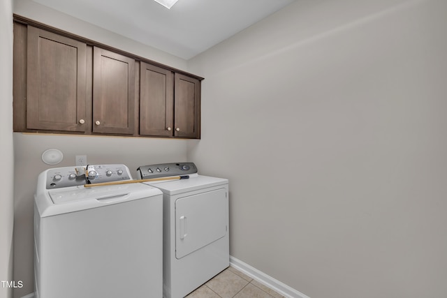 laundry room featuring cabinet space, separate washer and dryer, light tile patterned floors, and baseboards