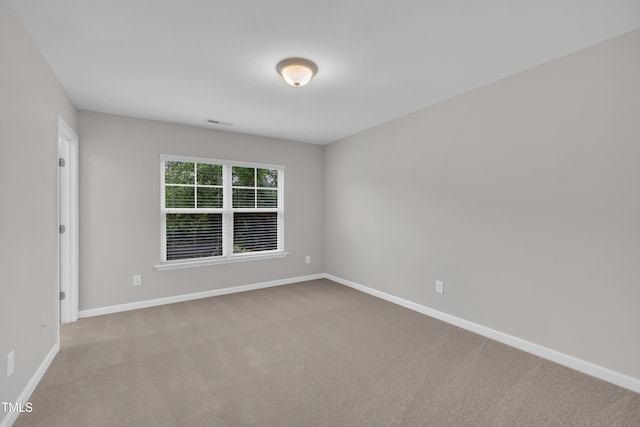 carpeted empty room featuring baseboards