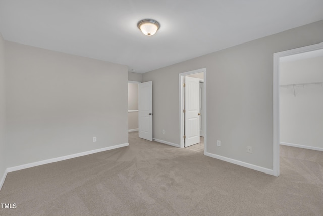 unfurnished bedroom featuring a spacious closet, carpet flooring, a closet, baseboards, and connected bathroom