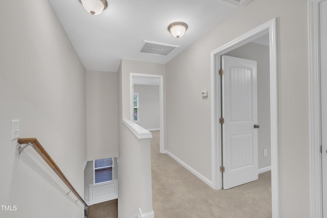 corridor with an upstairs landing, light colored carpet, and baseboards