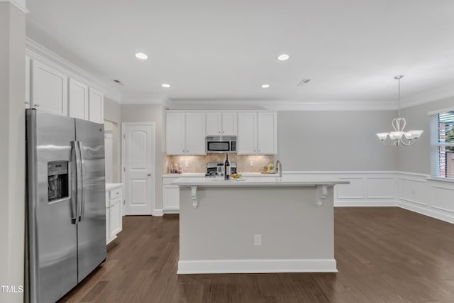 kitchen featuring appliances with stainless steel finishes, light countertops, white cabinets, crown molding, and dark wood-style flooring