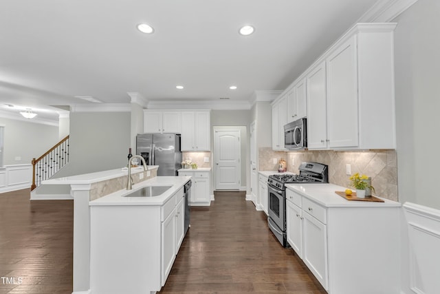 kitchen featuring stainless steel appliances, a sink, dark wood finished floors, an island with sink, and crown molding