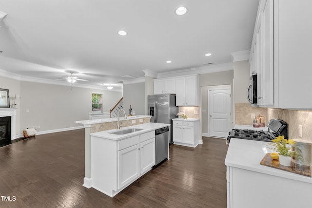 kitchen with a sink, appliances with stainless steel finishes, crown molding, a ceiling fan, and a center island with sink