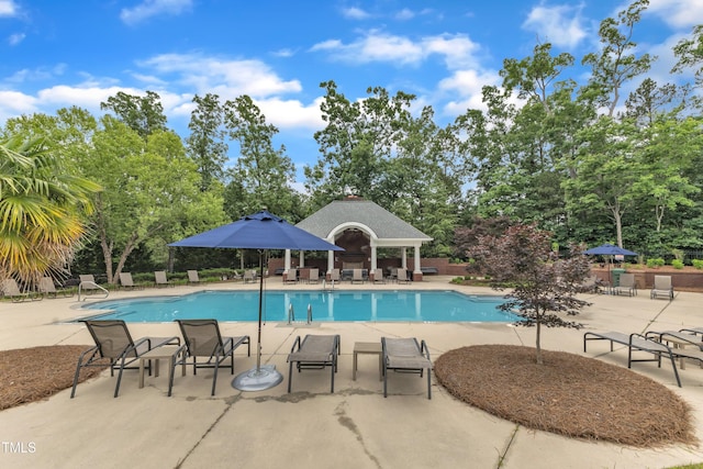 community pool featuring a patio area, a gazebo, and view of wooded area