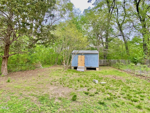 view of yard with fence, an outdoor structure, and a storage unit