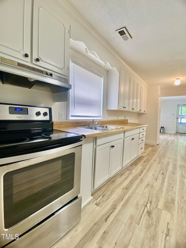 kitchen featuring under cabinet range hood, visible vents, a sink, light wood-style floors, and stainless steel electric stove