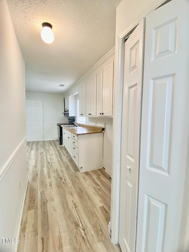 kitchen with white cabinets, black range with electric cooktop, light wood-type flooring, and a textured ceiling