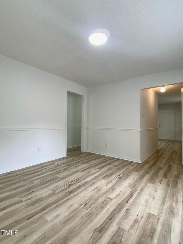 spare room with baseboards, wood finished floors, and a textured ceiling