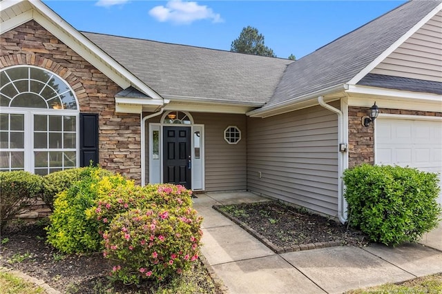 705 Fairfield Cir, Raeford, NC 28376 - view of exterior entry with stone siding, an attached garage, and roof with shingles