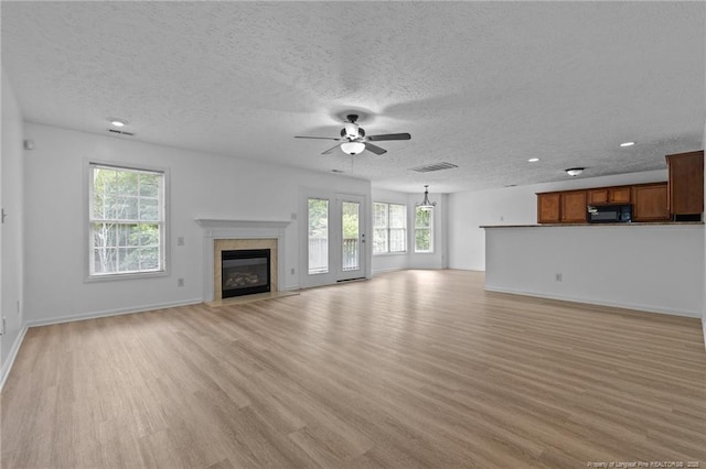 705 Fairfield Cir, Raeford, NC 28376 - unfurnished living room featuring healthy amount of natural light, light wood finished floors, ceiling fan, a high end fireplace, and a textured ceiling